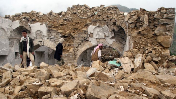 People walk on the rubble of a mosque, destroyed during fighting between pro-government forces and Iran-allied Houthi militia, in the al-Sarari area of Taiz province, Yemen