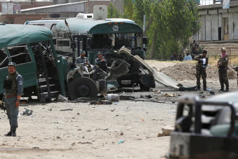 Afghan security forces inspect the damage on buses hit by suicide bombers at the site of an attack on the western outskirts of Kabul