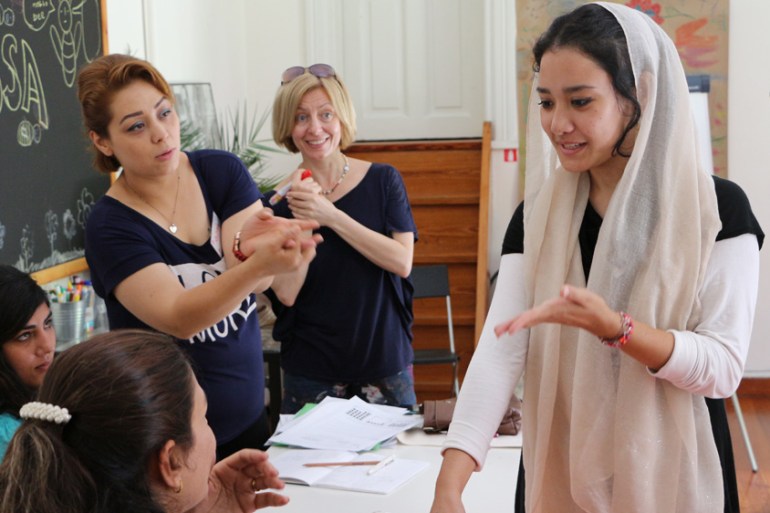 Fatima Ahmadi practices a greeting in Greek during an immersion language course at Melissa, while teacher Vicky Tanzou looks on [John Psaropoulos/Al Jazeera]