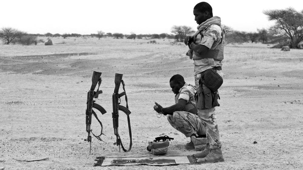 Peacekeepers from Niger pray by the side of the desert road [Marielle van Uitert/Al Jazeera]