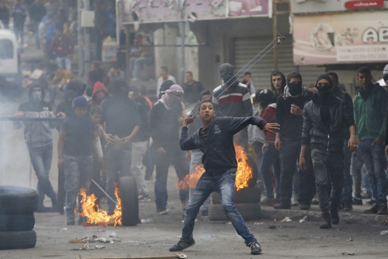 Palestinian protester uses a sling to hurl stones at Israeli troops