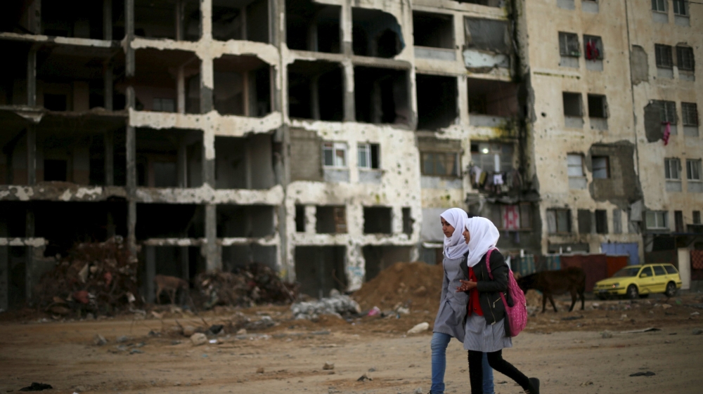 Palestinian schoolgirls walk past the remains of a residential building, destroyed during 2014 war in the northern Gaza Strip on February 10, 2016 [Reuters]