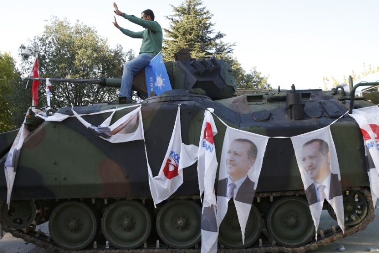 A man poses on an Armored Vehicle with portraits of Turkish President Tayyip Erdogan parked outside the parliament building in Ankara