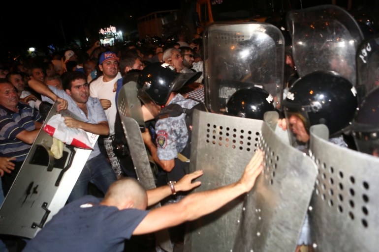 Riot police clash with demonstrators who had gathered in show of support for gunmen holding several hostages in police station in Yerevan
