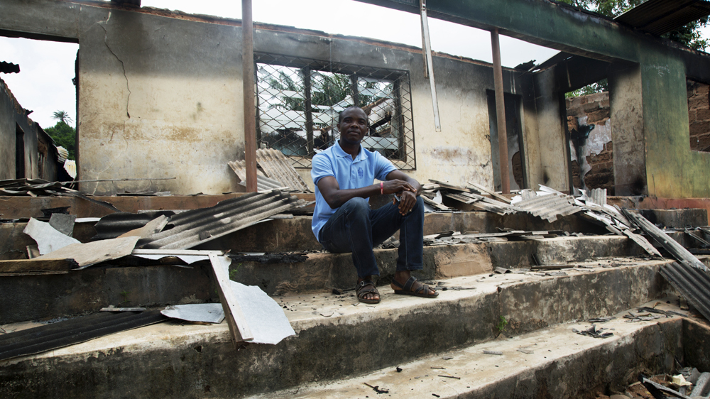 John Oriajaka sits amid the debris from a morning raid on his church by suspected Fulani herdsmen in Nimbo, southeastern Nigeria [Chika Oduah/Al Jazeera]