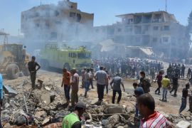Smoke rises while people gather at a damaged site after two bomb blasts claimed by Islamic State hit the northeastern Syrian city of Qamishli