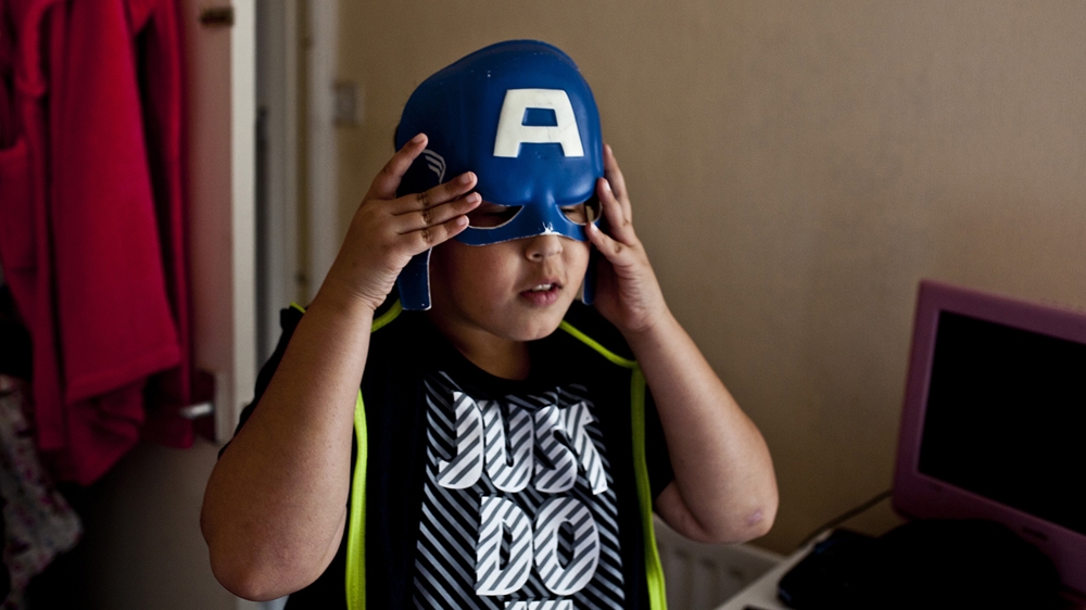 Hammad, Najma's son, plays with a 'Captain America' costume in his home [David Shaw/Al Jazeera] 