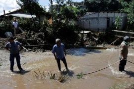 Resident walk through a river, past houses damaged by a mudslide in the aftermath of Tropical Storm Earl in the town of La Joya, in Puebla state, Mexico