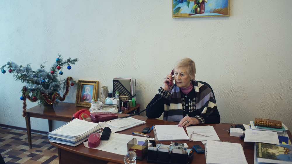School principal Klaudya Kharkovskaja in her office. She has been the school's head teacher throughout the war and refuses to leave [Kyrre Lien/Al Jazeera] 