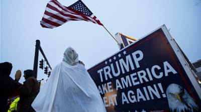 A protester in an outfit resembling a uniform of the Ku Klux Klan stands outside the site of a rally by Trump on February 8 [EPA]