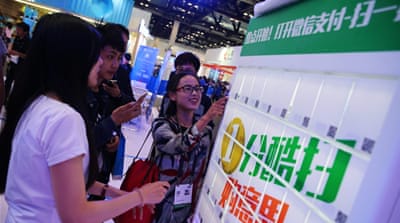 Visitors use the Wechat payment system to pay for gifts at the 2016 Global Mobile Internet Conference in Beijing, China