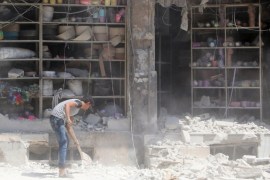 A civilian removes the rubble in front of a damaged shop after an airstrike in the rebel held al-Saleheen neighborhood of Aleppo