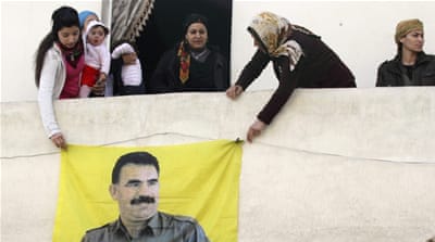 Kurdish women hang a picture of Ocalan, jailed leader of the PKK, in Sheikh Maksoud neighbourhood of Aleppo [Reuters]