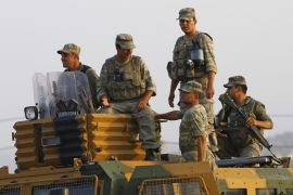 Turkish soldiers stand on top of an armoured vehicle near the Mursitpinar border crossing on the Turkish-Syrian border