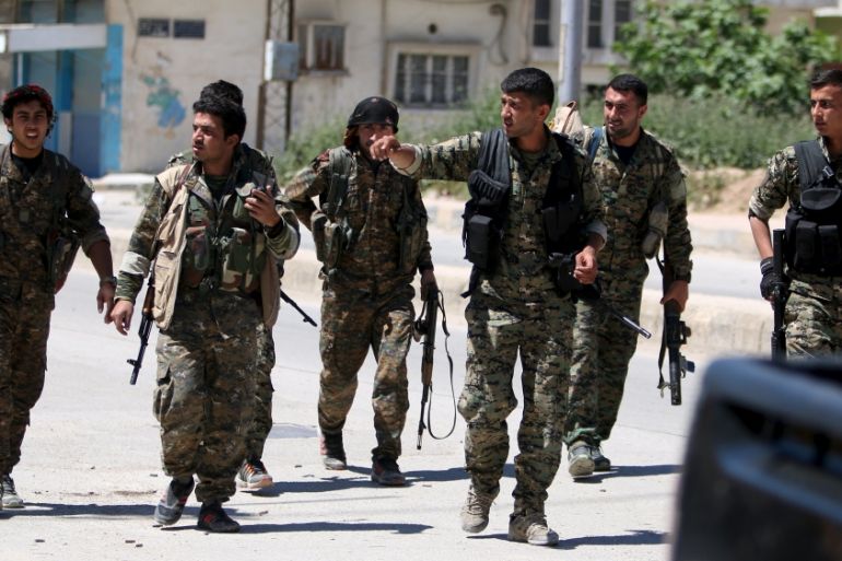 Kurdish fighters from the People''s Protection Units (YPG) walk along a street in the southeast of Qamishli city