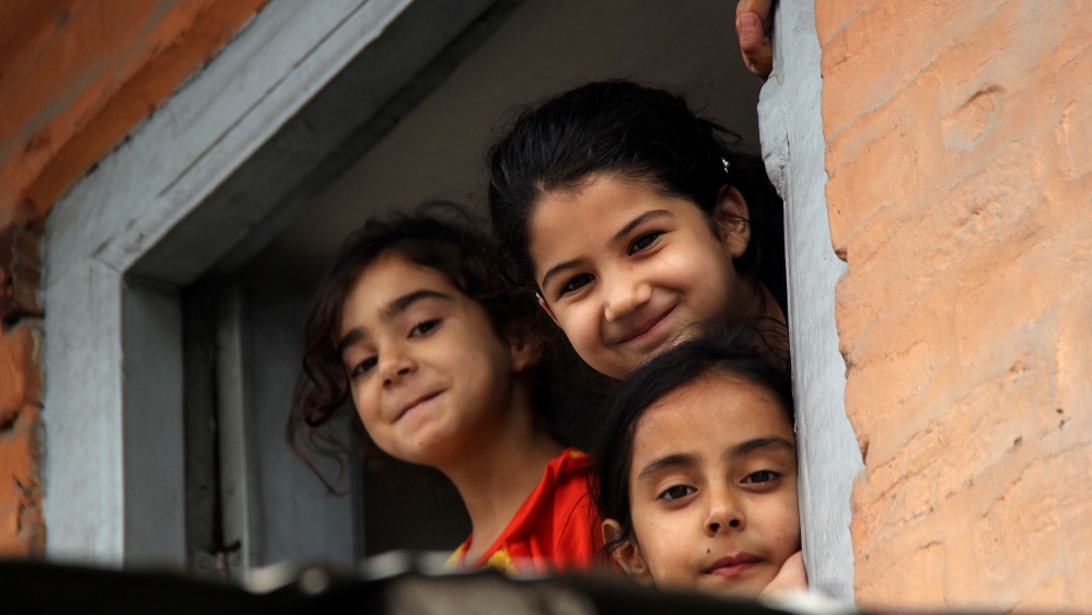 Young girls look from the window of their home in downtown Srinagar during the curfew [Aarabu Ahmad Sultan/Al Jazeera]