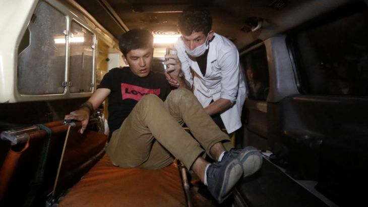 A wounded man is helped by a medic inside an ambulance following an attack at American University of Afghanistan in Kabul