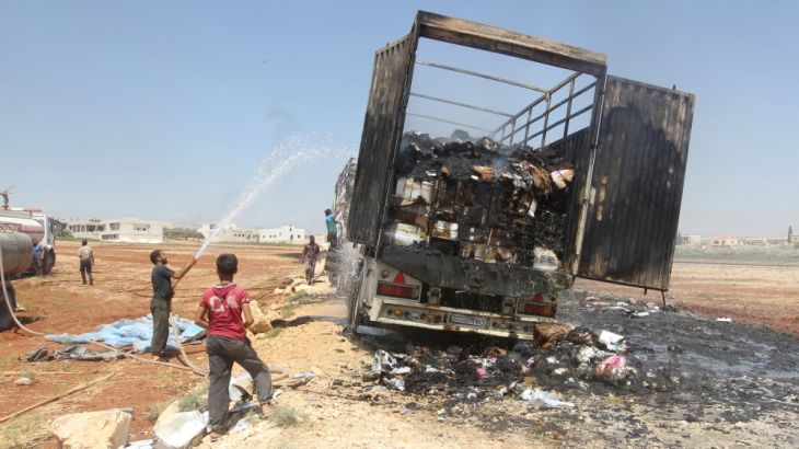 Men try to put out a fire of a loaded truck after an airstrike on a truck parking lot in the rebel-held town of Atareb in Aleppo province