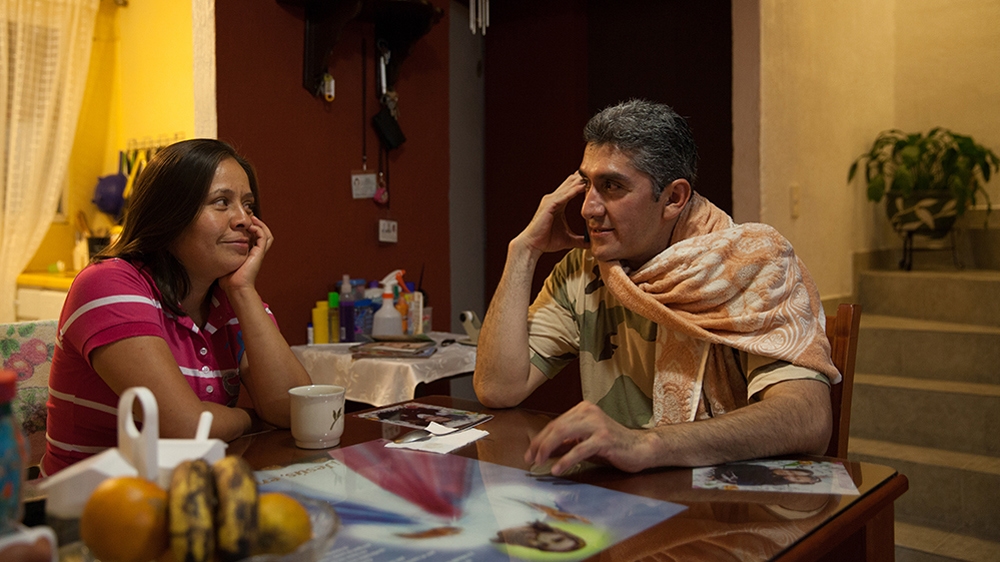 Donovan listens to classical music on his phone while drinking coffee with his wife at their home in Texcoco [Benedicte Desrus/Al Jazeera]