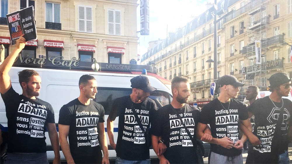 Demonstrators wear T-shirts demanding justice for Adama after the death of the 24 years old in July [nabeela zahir/Al Jazeera] 