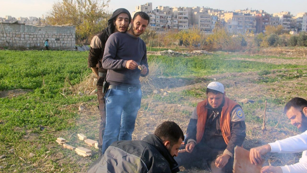 A photograph taken near Khaled's house in spring, during a barbeque with White Helmet volunteers. Khaled is seated in a white cap. Ibrahim, in jeans, is standing. [Courtesy Ibrahim al-Hajj]