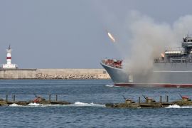 Amphibious vehicles drive in formation as the large landing ship Caesar Kunikov fires missiles during the Navy Day celebrations in Sevastopol
