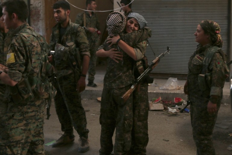 Syria Democratic Forces (SDF) female fighters embrace each other in the city of Manbij, in Aleppo Governorate