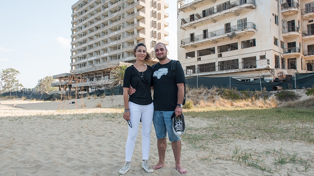 Turkish-Cypriot architect Ceren Bogac and Greek-Cypriot urban planner Nektarios Christodoulou stand in front of empty buildings in Varosha [Wojtek Arciszewski/Al Jazeera]