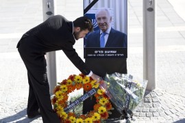 People place flowers on a picture of the late Shimon Peres [EPA]