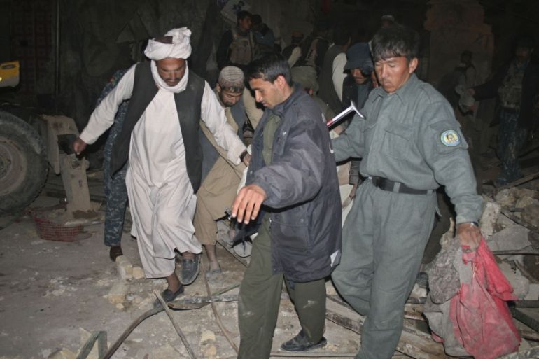 Afghan police and locals carry a wounded man from the site of a suicide attack in Trinkot city