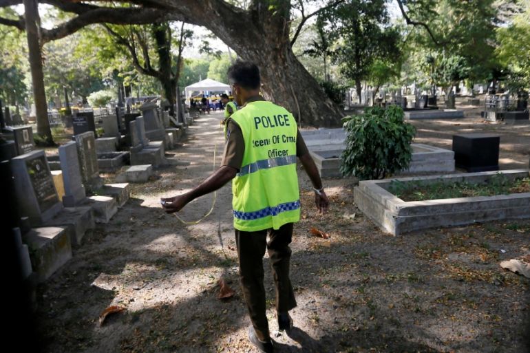 A police officer from the criminal investigations department prepares to exhumes the body of Lasantha Wickrematunge at a cemetery in Colombo