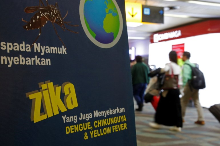 Airline passengers walk past a banner about the Zika virus shortly after landing from Singapore at Soekarno-Hatta airport in Jakarta