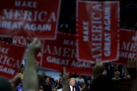 Republican presidential nominee Donald Trump is framed by "Make America Great Again" signs as he speaks onstage during a campaign rally in Akron