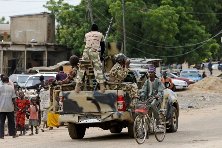 Nigerian soldiers hold up a Boko Haram flag that they had seized in the recently retaken town of Damasak, Nigeria