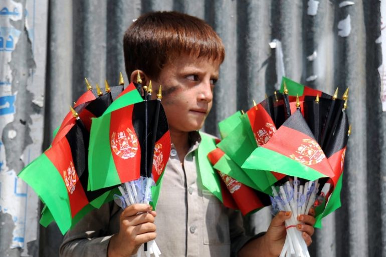 An Afghan boy sells the national flag on a roadside in Jalalabad, Afghanistan [EPA]