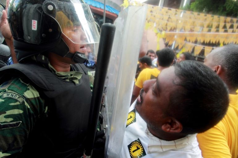 A supporter of Maldives presidential candidate Mohamed Nasheed shouts slogans in front of a police officer during a protest in Male, after the presidential run-off election was called off