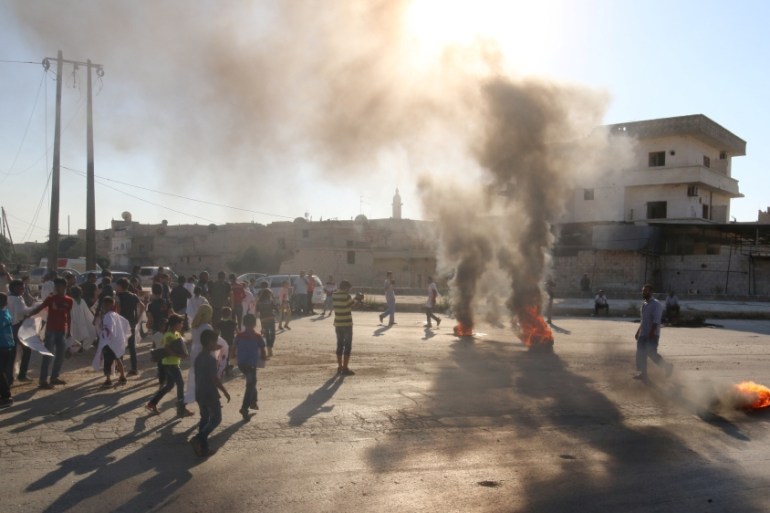 People gather near burning tyres during a demonstration against forces loyal to Assad and calling for aid to reach Aleppo near Castello road in Aleppo, Syria [REUTERS]