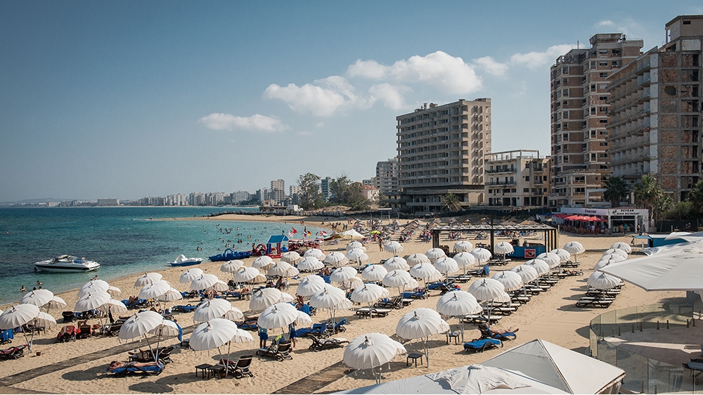 Deserted towers in Varosha overlook a thriving beach resort in the Cypriot city of Famagusta [Wojtek Arciszewski/Al Jazeera]