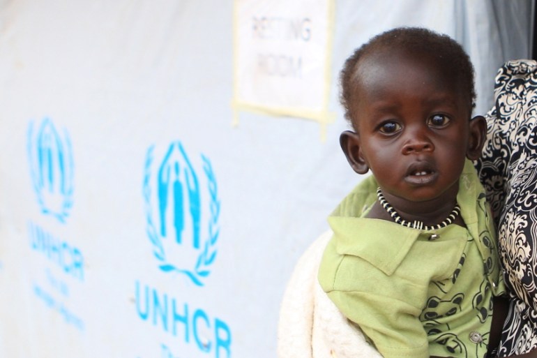 A South Sudanese refugee woman carries her child at the UNHCR managed refugees reception point at Elegu, within Amuru district of the northern region near the South Sudan-Uganda border