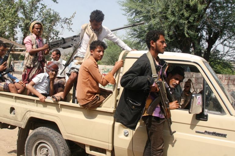Pro-government fighters ride on the back of a truck at al-Dhabab area after they took it from Houthi fighters outside the southwestern city of Taiz, Yemen