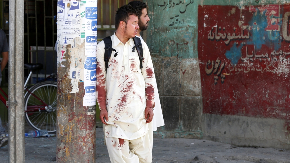 An Afghan man with blood-stained clothes stands at the side of blast after a suicide attack in Kabul, Afghanistan, on July 23, 2016 [Omar Sobhani/Al Jazeera]