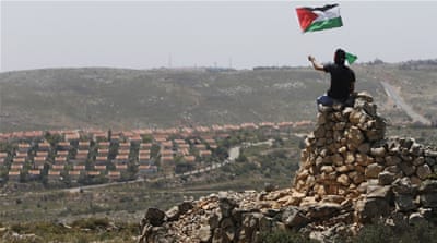 A protester waves a Palestinian flag in front of the Jewish settlement of Ofra during clashes near the West Bank village of Deir Jarir near Ramallah on April 26, 2013 [Reuters]