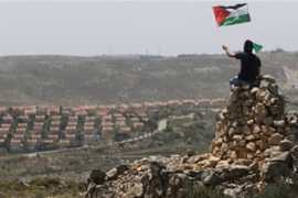 A protester waves a Palestinian flag in front of the Jewish settlement of Ofra