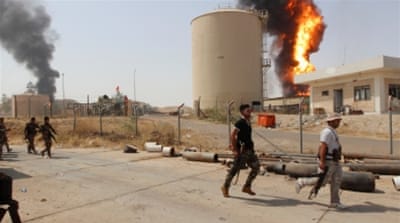 Kurdish Peshmerga forces walk as smoke rises after an attack at Bai Hassan oil station, northwest of Kirkuk, Iraq [Reuters]