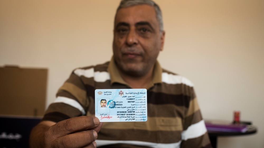 Jordanian farm owner Mansour al-Fawaz holds up a work permit that he processed through the Ministry of Labour for one of his Syrian workers [Alisa Reznick/Al Jazeera]