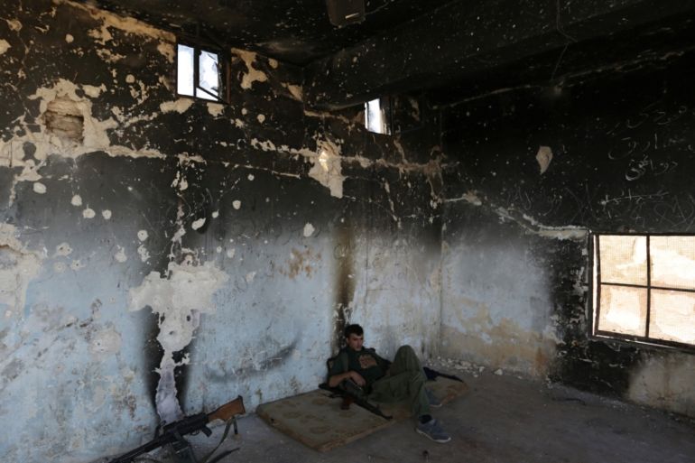 A rebel fighter rests inside a damaged room in Marea city, northern Aleppo province