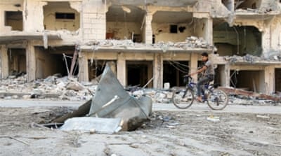 
A man rides a bicycle near damaged ground in the rebel-held besieged al-Sukkari neighbourhood of Aleppo, Syria [Reuters]
