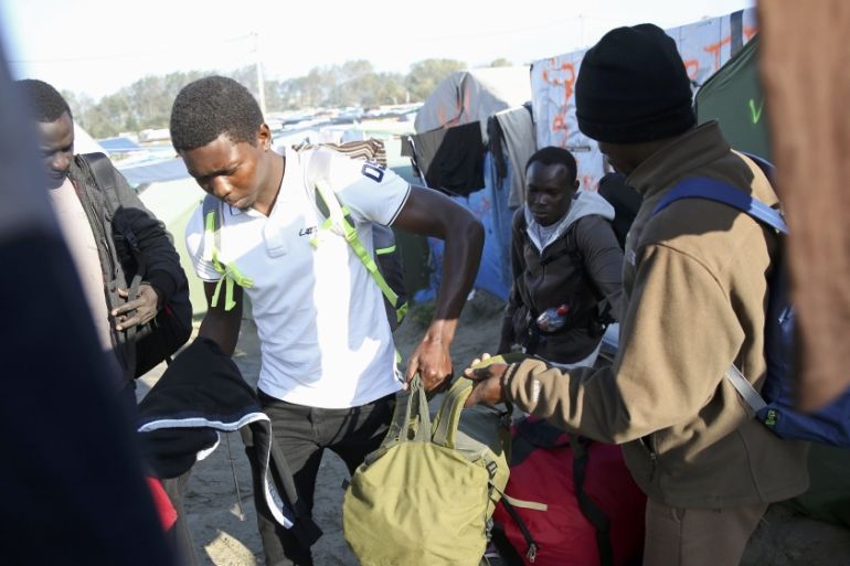 A migrant carries his belongings as he walks past t
