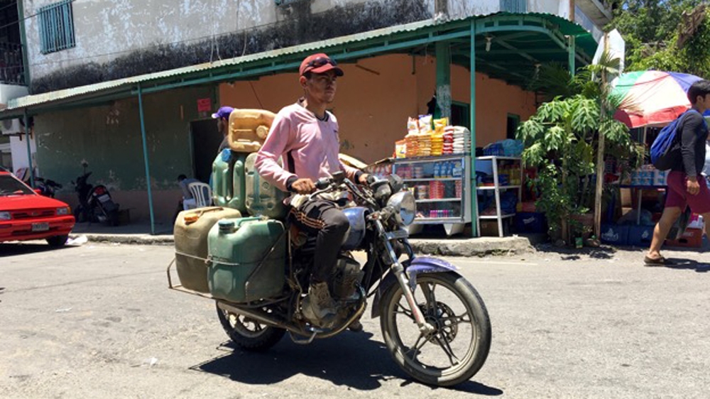 A man smuggles petrol from Venezuela to Colombia, where pop-up petrol stations sell fuel at a lower price than legal operations [Anne Bouleanu/Al Jazeera]