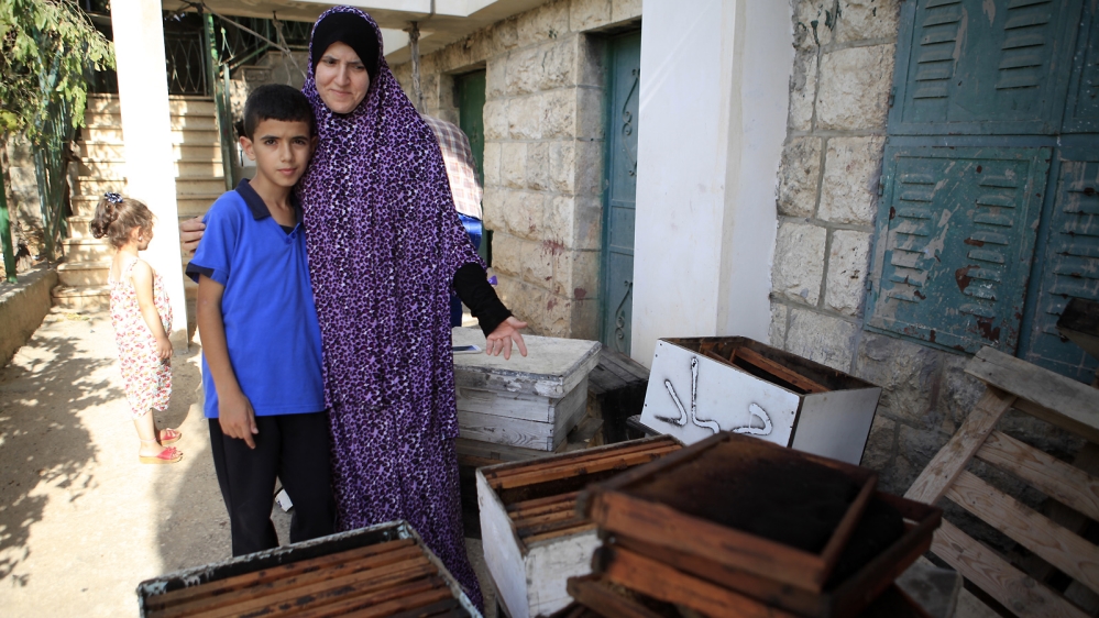 Taha shows her empty beehives: 'Last year, we had bees so we could produce our own honey, but all the bees died due to lack of water; there are not enough flowers' [Eloise Bollack/Al Jazeera] 